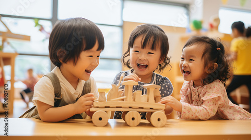 日本の幼稚園児3人が私服で木のおもちゃを使って,笑顔で遊んでいる写真、背景保育ルーム、木育/幼児教育 photo