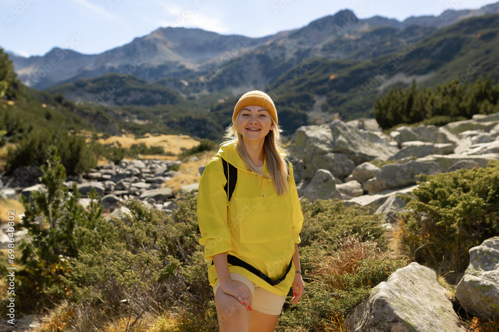 Excited woman walking through landscape outdoors. An active girl enjoys her vacation in the forested mountains. Smiling tourist on a hike. A joyful explorer going on a tourist adventure.