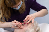 The beautician removes facial hair during her client's visit.