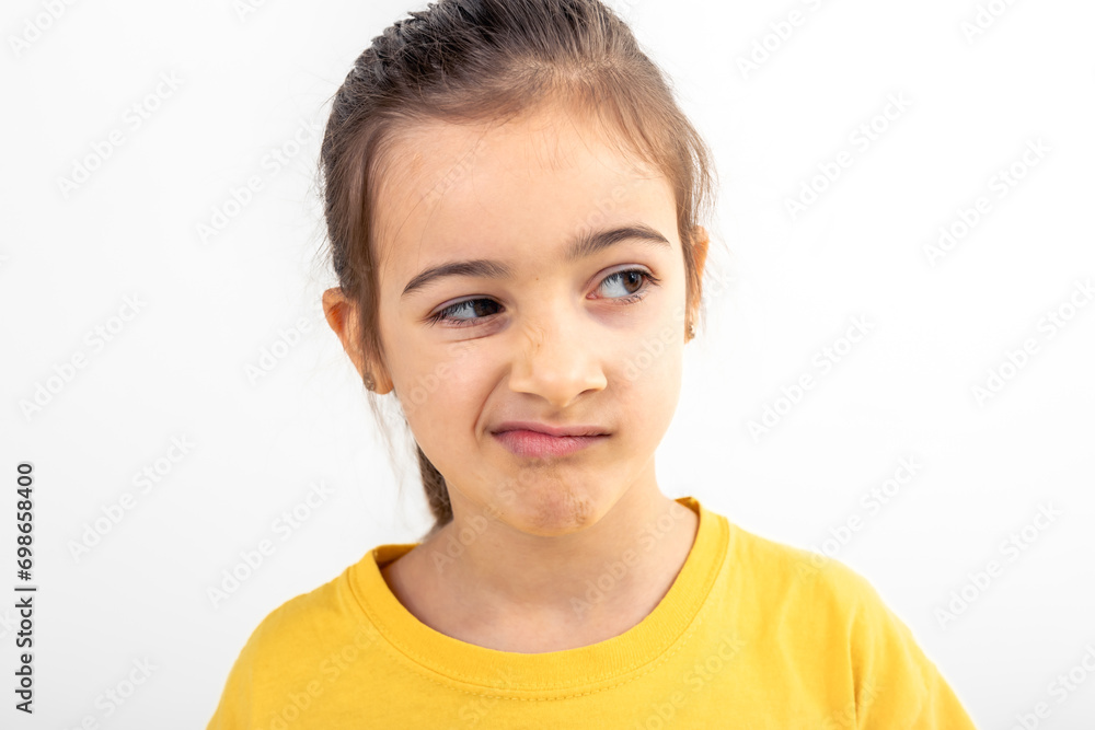 A little girl grimaces with displeasure on a white background, isolated. A little girl grimaces with displeasure on a white background, isolated.