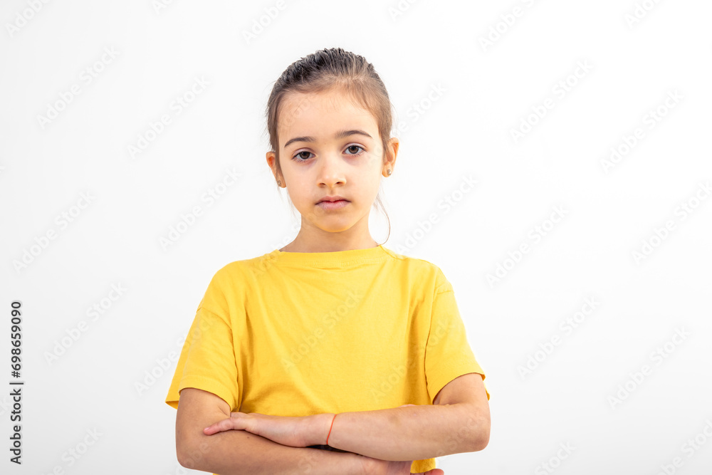 Sad school girl dressed yellow t-shirt arms folded on white background. Sad school girl dressed yellow t-shirt arms folded on white background.