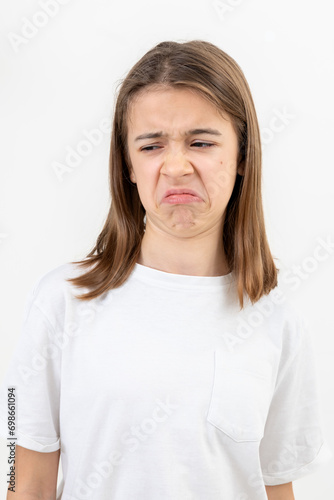 Canvas Print A teenager girl grimaces with displeasure on a white background, isolated