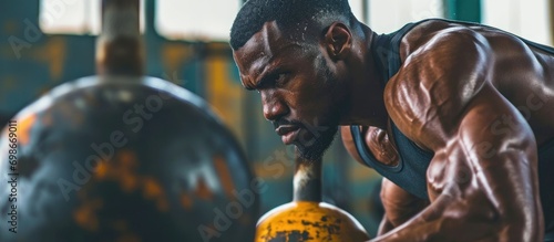 Black man uses kettlebell for rigorous fitness training, focusing on sports exercise, muscle growth, and power goals.
