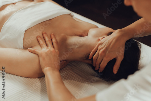 Hands of female chiropractor massaging shoulders of young woman lying on massage table. Concept of physical therapy treatment  neck pressure point