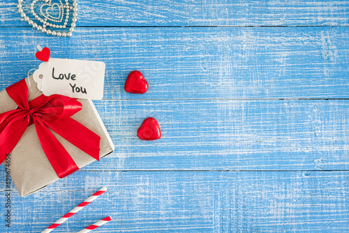 Valentine's Day background with gift box on blue wooden background, top view.
