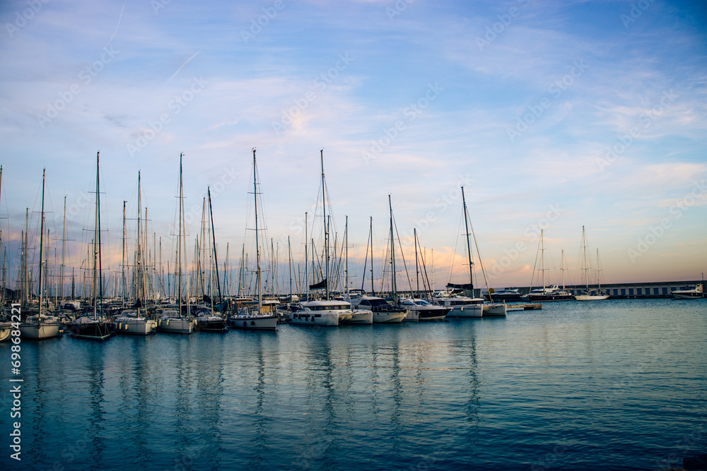 Sailboat harbor in the port evening photo. Beautiful moored sail yachts in the sea, Catalonia. Bright sunset and dusk