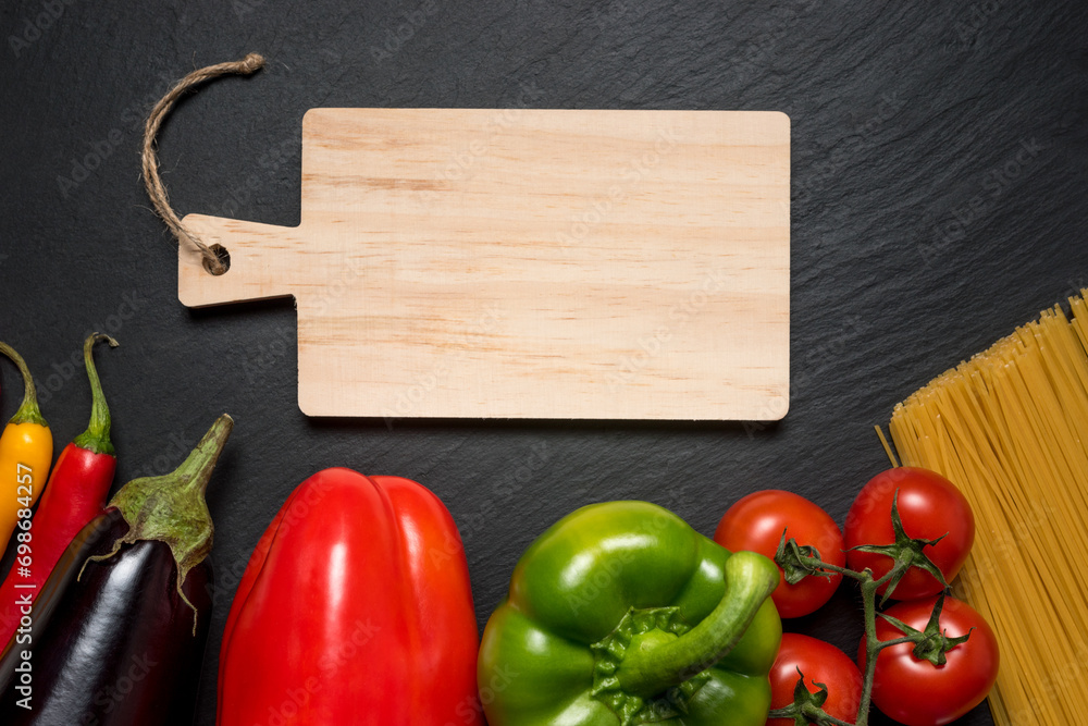 Colorful vegetables and spaghetti on black background with copy space.