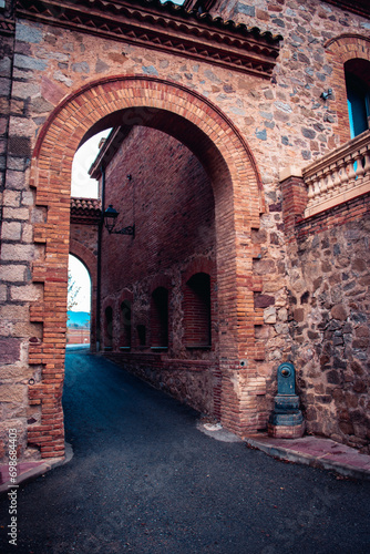 The exterior of an old farm concept photo. An arch through which you can see the backyard an old stone building. © Natalya Nepran