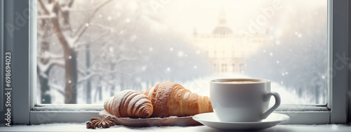 delicious hot coffee and a croissant on the windowsill. outside the window is winter