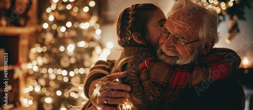 Vászonkép Elderly man hugs granddaughter, gets Christmas present at home.