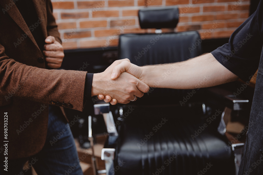 Happy Barber greeting male client in barbershop, warm toning photo Happy Barber greeting male client in barbershop, warm toning photo