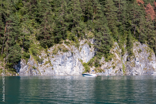 Rocky cliffs along the lakeshore of alpine lake Weissensee in Carinthia, Austria. Scenic view from tourist ferry in summer. Bathing lake and mountains of Austrian Alps. Untouched nature in summer photo