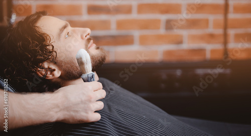 Barber shaving man with sharp steel razor, banner barbershop warm retro old toning © Parilov