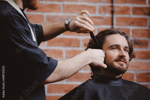 Happy hipster man in barber chair getting haircut from barbershop, warm toning