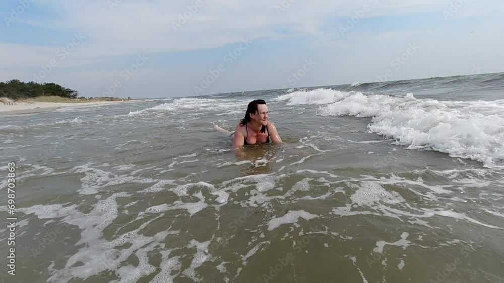 Woman lying on the shore and enjoying the sea waves on a summer day. Slow Motion. Sea shore, seascape, summer vacation Woman lying on the shore and enjoying the sea waves on a summer day. Slow Motion. Sea shore, seascape, summer vacation