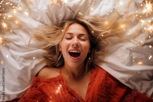 Young blonde woman having orgasm. Beautiful woman with open mouth and closed eyes enjoying sex lying among fireworks. Sparklers as a symbol of orgasm. Sexual experience, masturbation, cunnilingus.