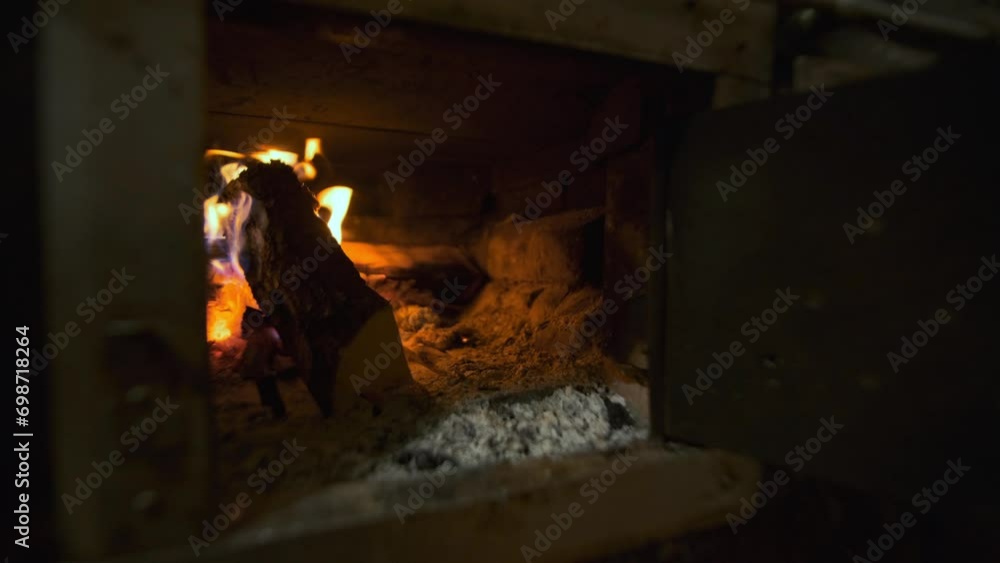 A hand puts wood in the stove. Nice close up view of wooden logs that burn in oven or in fireplace. Heating houses to heat families and residents. A hand puts wood in the stove. Nice close up view of wooden logs that burn in oven or in fireplace. Heating houses to heat families and residents.
