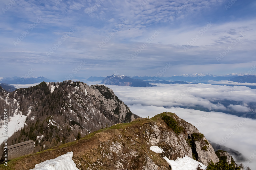 Scenic view from mountain peak Schwarzkogel to Dobratsch in Karawanks mountains in Carinthia, Austria. Magical atmosphere in remote landscape in Slovenian Austrian Alps. Misty fog and clouds in valley