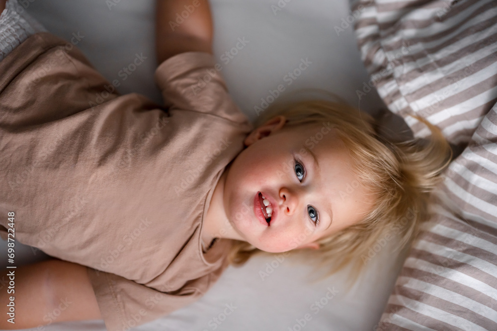 Cute caucasian blonde baby child on white sheets on the bed Cute caucasian blonde baby child on white sheets on the bed