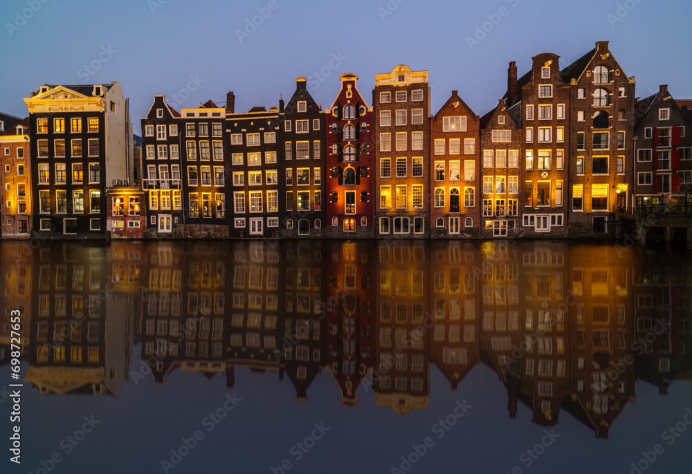 The golden hour reflects on Amsterdam's iconic canal houses, mirrored perfectly in the still water The golden hour reflects on Amsterdam's iconic canal houses, mirrored perfectly in the still water