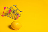 Lemon in shopping cart on yellow background