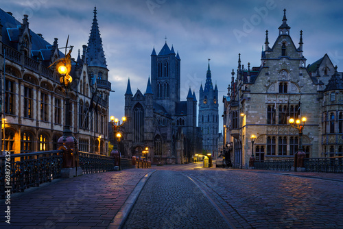 Historical buildings and street lights at dawn in Ghent with Saint Bavo's Cathedral in the background photo