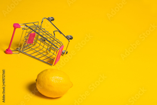 Lemon in shopping cart on yellow background photo