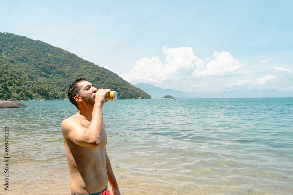 man drinking beer can at beach