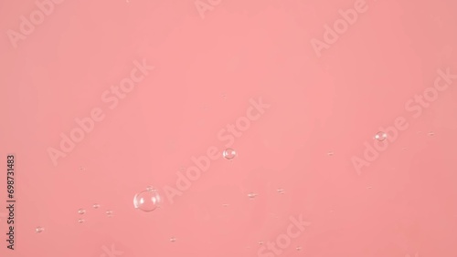 The surface of water on a pink background. Bubbles are visible on the water. photo
