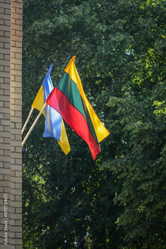 Lithuanian and Ukrainian flags on the brick wall, green nature in background