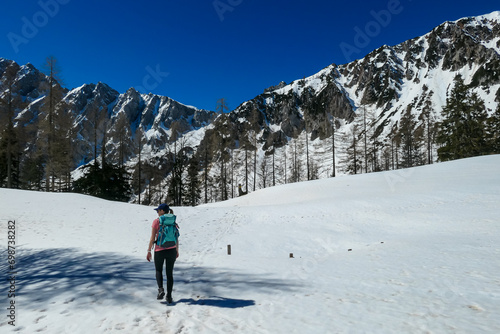 Woman on snow covered hiking trails with scenic view of Karawanks mountains in Carinthia, Austria. Looking at snow capped summit of Vertatscha and Hochstuhl. Remote alpine landscape in Bodental
