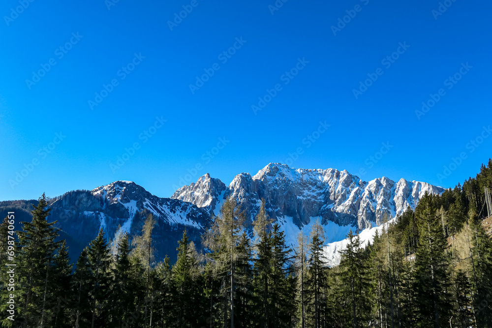 Panoramic view of Karawanks mountain range on sunny day in Carinthia, Austria. Looking at snow capped summit of Vertatscha and Hochstuhl. Remote high alpine landscape in Bodental, Austrian Alps
