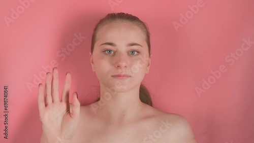The pink background depicts a young, makeup free girl. She is lying supposedly underwater and looking at the camera, leaning her hand against the water or glass. At this time the water creates waves photo