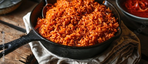 Nigerian party jollof rice cooked in a cast iron pot, with smoky and flavorful red rice. photo