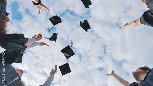 Fotografía Happy college graduates tossing their caps up at sunset.