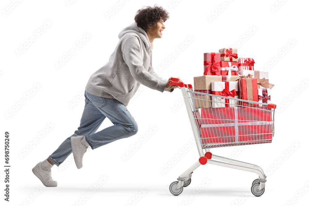 Young man running with present boxes in a shopping cart Young man running with present boxes in a shopping cart