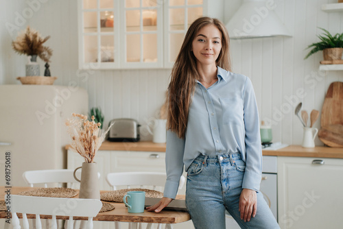 Professional woman in a blue blouse and jeans standing in a vintage kitchen  poised and stylish