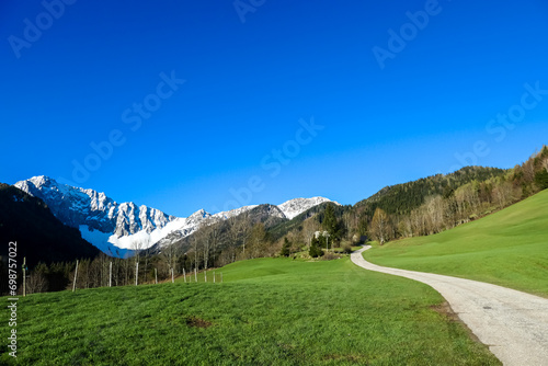 Panoramic hiking trail along lush green alpine meadows and forest with scenic view of Karawanks mountain range in Carinthia, Austria. Remote villages on alpine landscape in Bodental, Austrian Alps photo