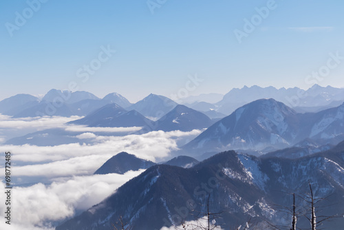 Panoramic aerial view of snow capped mountain ranges of Karawanks, Julian and Kamnik Savinja Alps in Carinthia, Austria. Winter wonderland in remote Austrian Alps. Valley covered with mystical fog