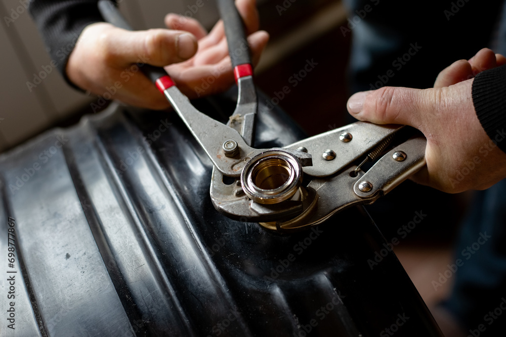 A plumber screws a fitting onto a water tank. Installation of a summer shower system A plumber screws a fitting onto a water tank. Installation of a summer shower system