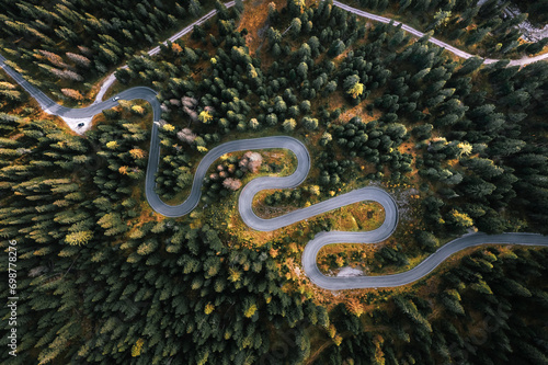Obraz na płótnie Car driving on a serpentine road leading through Italian Dolomites in autumn colors. Curvy road surrounded by pine forest. w salonie