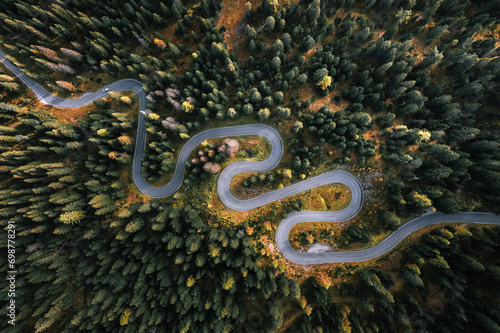 Obraz na płótnie Car driving on a serpentine road leading through Italian Dolomites in autumn colors. Curvy road surrounded by pine forest. w salonie