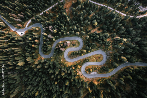 Obraz na płótnie Car driving on a serpentine road leading through Italian Dolomites in autumn colors. Curvy road surrounded by pine forest. w salonie