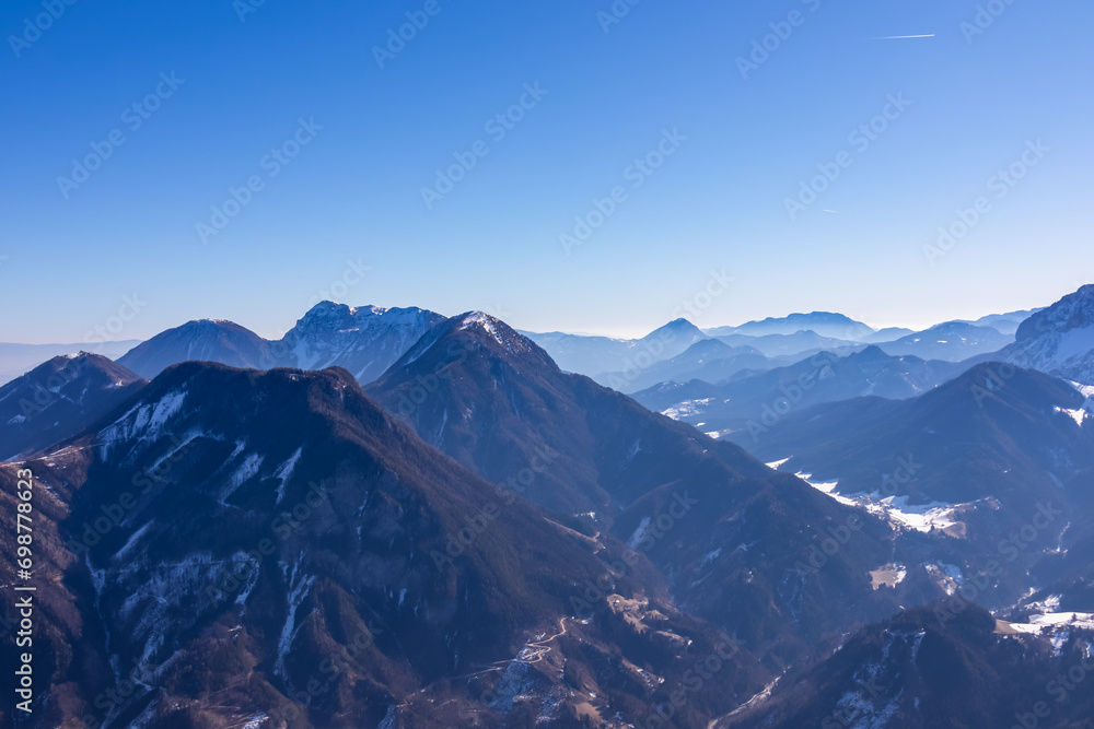 Fototapeta premium Scenic view on snow capped mountain peaks of Karawanks, Julian and Kamnik Savinja Alps in Carinthia (Kaernten), Austria. Winter wonderland in Austrian Alps, Europe. Aerial view from Ferlacher Horn
