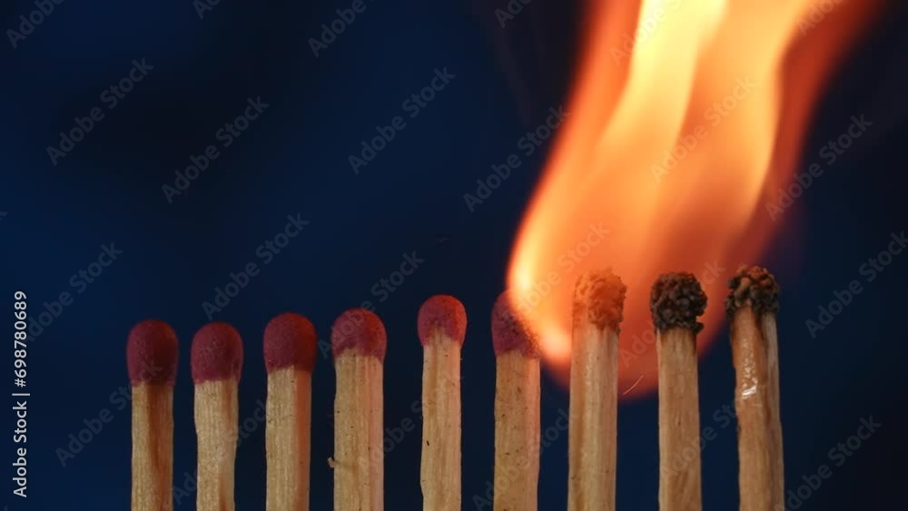 A row of matches where one flares up and passes its fire to the next. Cascade of flame, transfer of energy. Macro shot of the transition of flame from one match to another. A row of matches where one flares up and passes its fire to the next. Cascade of flame, transfer of energy. Macro shot of the transition of flame from one match to another.