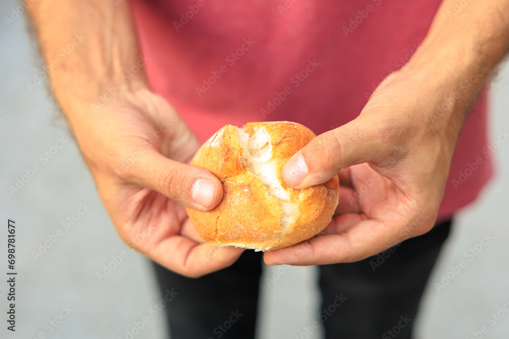 A man's hand holds a round bun, snack and fast food concept. Selective focus on hands with blurred background