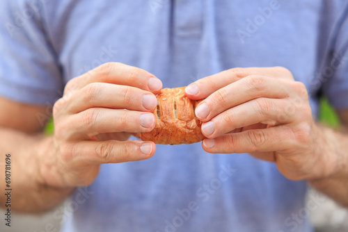 A man's hand holds a mini puff pastry with cheese, snack and fast food concept. Selective focus on hands