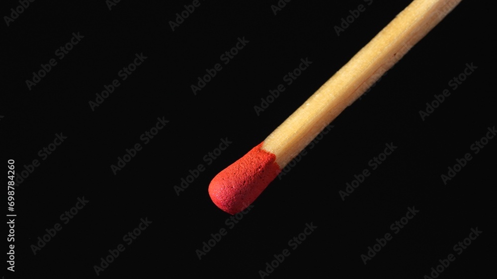 A macro shot of a matchstick against a black background. A wooden match with red sulfur. A macro shot of a matchstick against a black background. A wooden match with red sulfur.