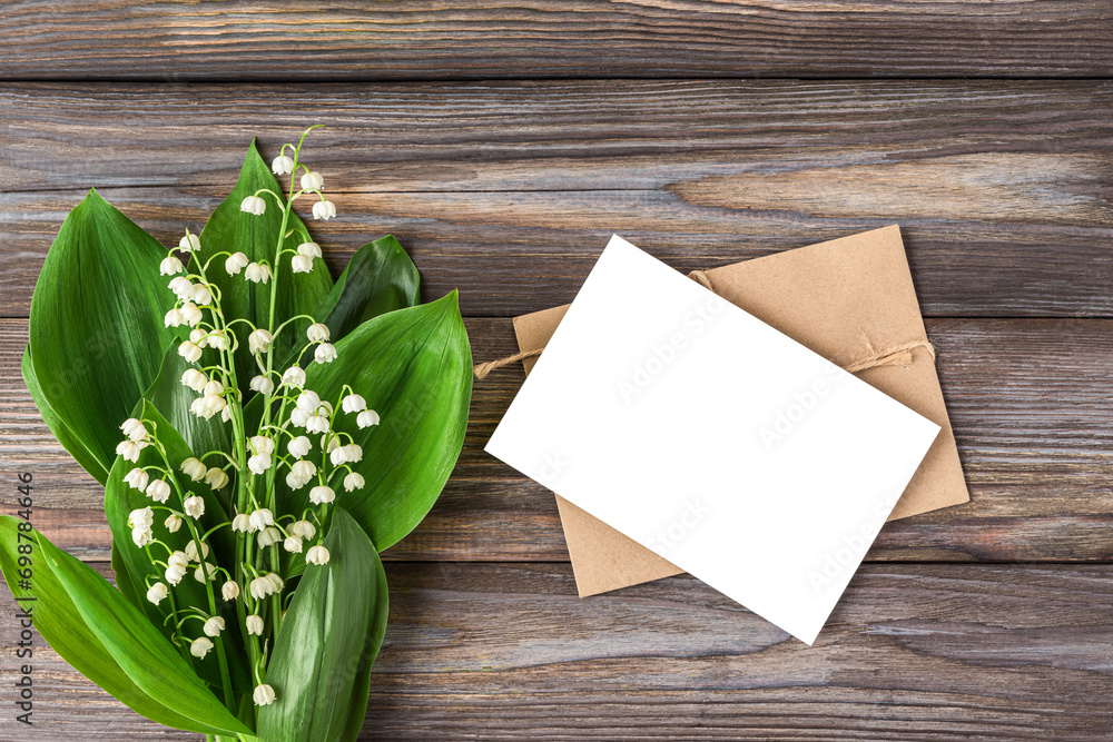 Blank greeting card with spring Lily of the valley flowers bouquet on rustic wooden background. Wedding invitation. Womens day, Valentines day card. Mock up. Flat lay Blank greeting card with spring Lily of the valley flowers bouquet on rustic wooden background. Wedding invitation. Womens day, Valentines day card. Mock up. Flat lay