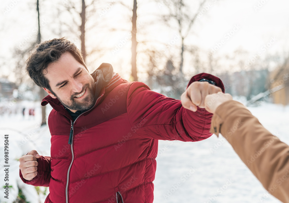 Happy smiling man doing fist bump with an unrecognizable person outdoors. Happy smiling man doing fist bump with an unrecognizable person outdoors.
